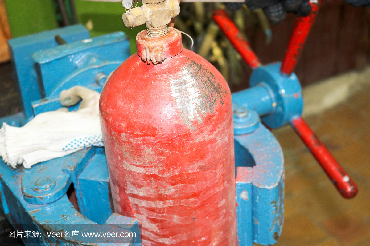 工廠車間藍(lán)色鐵金屬大型工業(yè)虎鉗和紅色滅火器氣缸